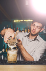 Young Barman's making shot cocktail, pouring syrup into glass