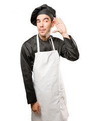 Happy young chef doing a listen gesture