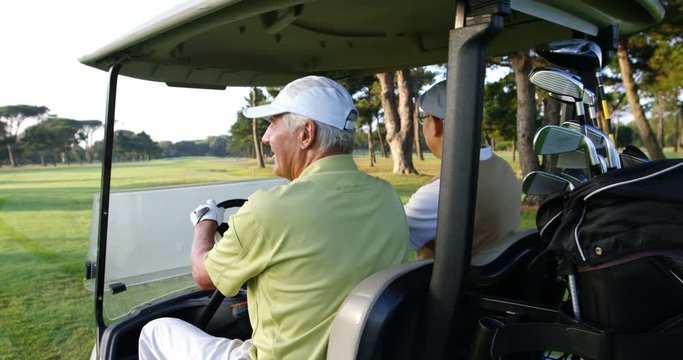 Two golfers driving in their golf buggy at golf course