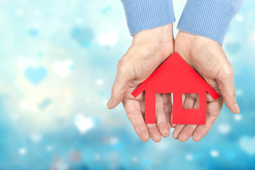 rotes Haus aus Papier in den Händen halten