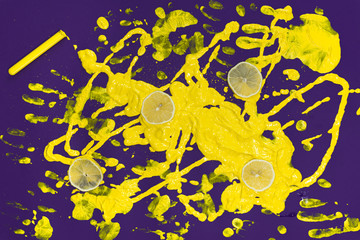 Splash of yellow paint on purple background top view