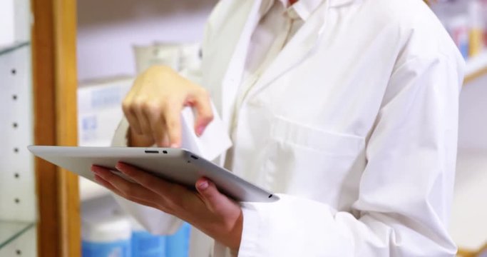 Pharmacist using digital tablet while checking medicine in pharmacy