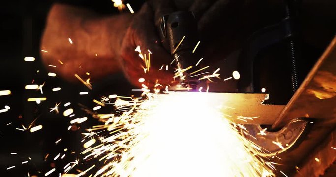 Mid-section of welder using welding torch in workshop 4k