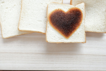 bread with heart shape burn on wooden table