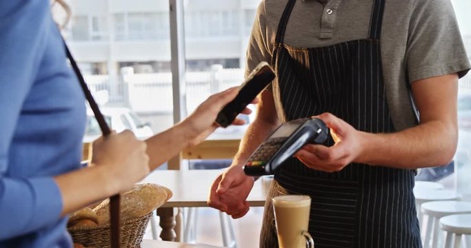 Woman paying bill through NFC technology in cafe 4k