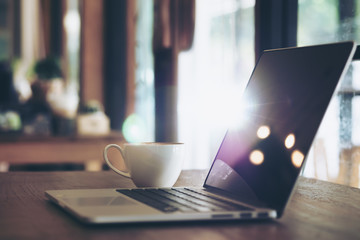 Drink & technology image of hot latte art coffee with laptop on wood table in cafe with light , bokeh flare and abstract 