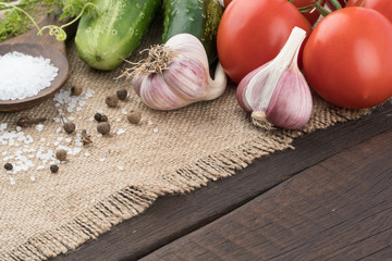 Fresh cucumbers, tomatoes with garlic on an old dark wood table.