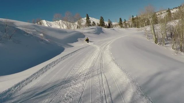 Snowmobile winter ride mountain trail forest POV. Snowmobile trail ride across high mountain meadow and forest at high speed high in central Utah in winter. Recreation and fun.