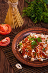 Penne pasta in tomato sauce with chicken, tomatoes decorated with parsley.