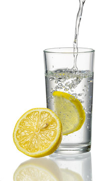 Glass of water with splashed lemon isolated on white