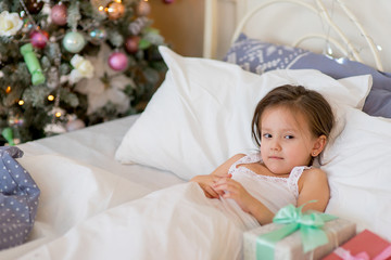 Obraz na płótnie Canvas Child girl wake up in her bed in Christmas morning