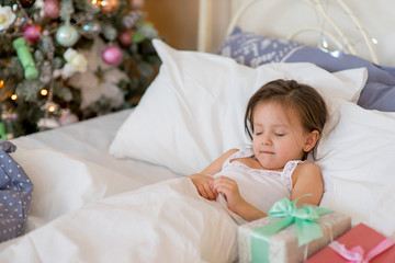 Fototapeta na wymiar Child girl wake up in her bed in Christmas morning