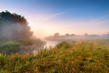 Summer misty sunrise on the river. Foggy river in the morning. S