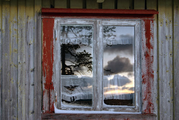 altes Fenster mit gespiegeltem Himmel  in verwitterter Holzwand