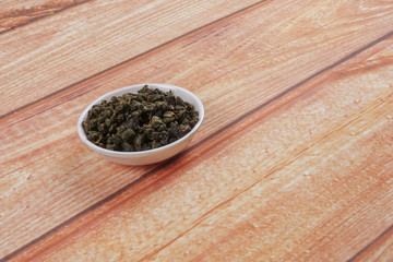 dried chinese tea leaves in a small bowl over wooden background