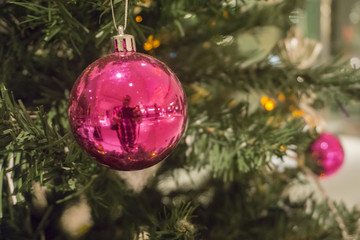 Closeup of red bauble hanging from a decorated Christmas tree. Retro filter effect.