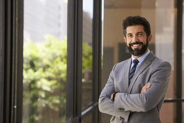 Fototapeta premium Smiling Hispanic businessman with arms crossed, to camera