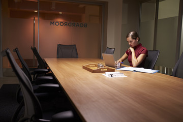 Young white businesswoman working alone late in an office