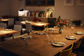 Close focus view on row of empty water and wine transparent glasses on served for holiday main dinner table in big loft room at evening, low lightning