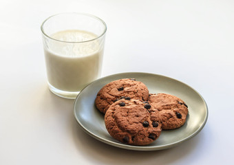 Овсяное печенье на плоской тарелке и стеклянный стакан молока