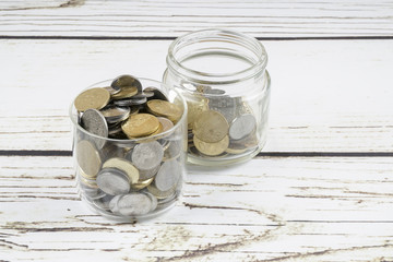 Glass jar with coins on wooden background