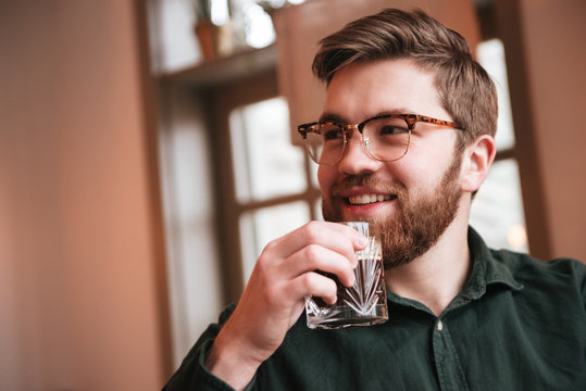 Attractive bearded young man drinking whiskey.
