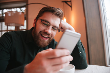 Happy bearded young man using smartphone.
