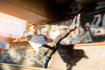 Fototapeta na wymiar Guy on rollerblades doing trick. Young rollerblader outdoor. Speed and balance.