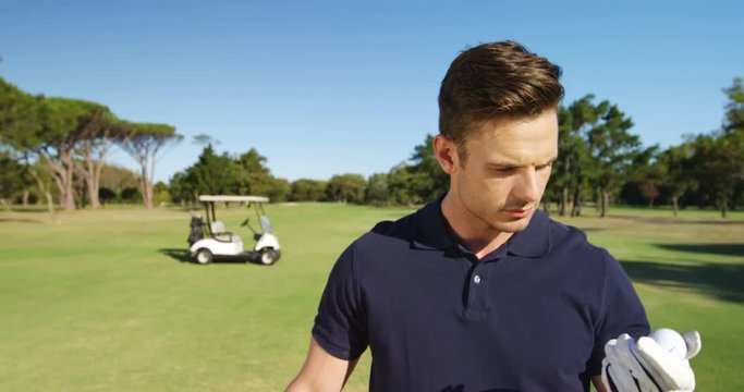 Happy golf player examining the golf ball at golf course
