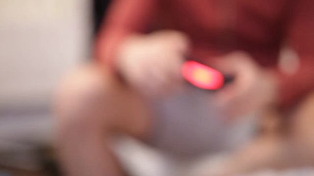 Blurring background. People with a controller in hands playing video game console.