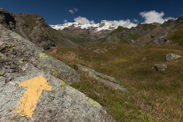 Yellow arrow painted on a rock in italian Alps