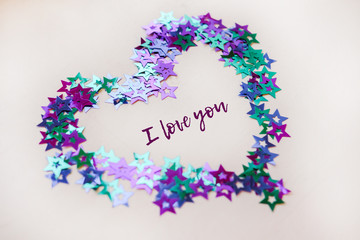 gift heart for Valentine's Day on the background of glittering confetti in the shape of stars. The 14th of February. Heart with the words I love you, symbol of love Valentine's Day
