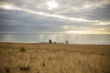 group of people wandering on the beach at sunset by a cloudy winter day