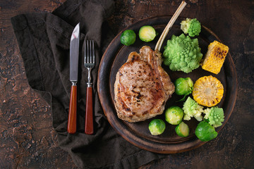 Grilled veal tomahawk steak with vegetables brussels sprouts, romanesco and corn cobs served with...
