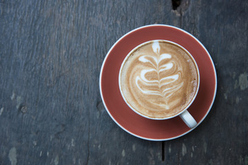 above cup of hot latte art coffee on wooden table.