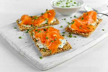Homemade Crispbread toast with Smoked Salmon, Melted Cheese and cress salad. on white wooden board