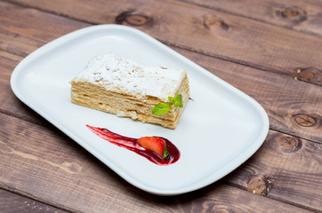 Napoleon cake on a white plate with berries