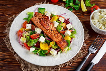 Fried Salmon steak with fresh vegetables salad, feta cheese. concept healthy food.