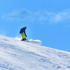 Male snowboarder on the slope sliding down the hill