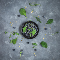 Fresh blueberry and spinach leaves on stone background. Flat lay, top view, square
