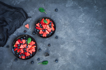 Fruit salad with watermelon, strawberry, blueberry on stone background. Valentine's day. Flat lay,...