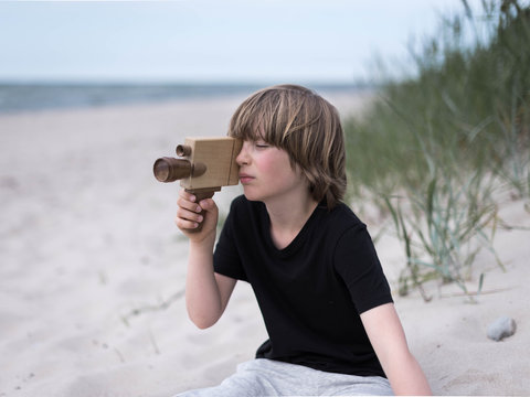 young boy filming on beach