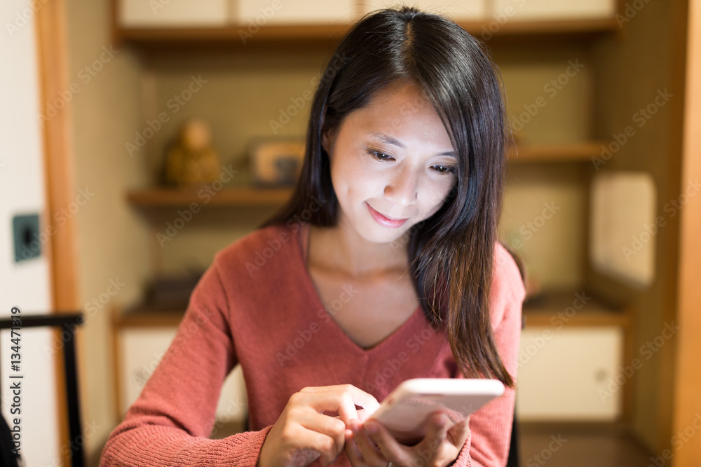 Poster Woman looking at cellphone in Japanese restaurant