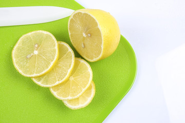 Fresh lemon and slices on green board with knife. Top view
