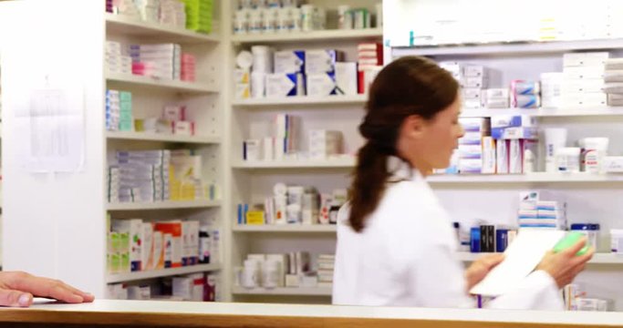 Customer giving prescriptions of medicine to pharmacist in pharmacy