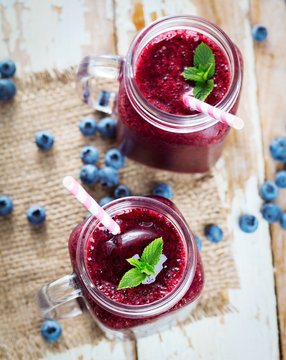 Blueberry smoothie with mint in glass on wooden table