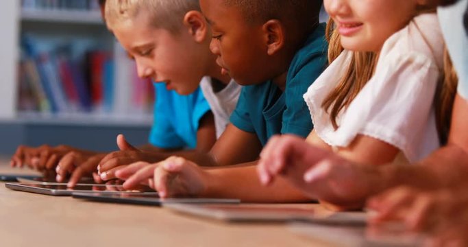 School kids using digital tablet in library at elementary school 4k