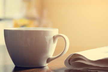 Cup of coffee and newspaper on wooden table. Vintage effect.