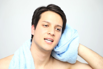 Obraz na płótnie Canvas young man toweling his face, men's skin care concept