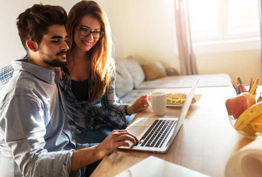Young married couple sitting at the morning in they living room and using laptop.Online stock market.